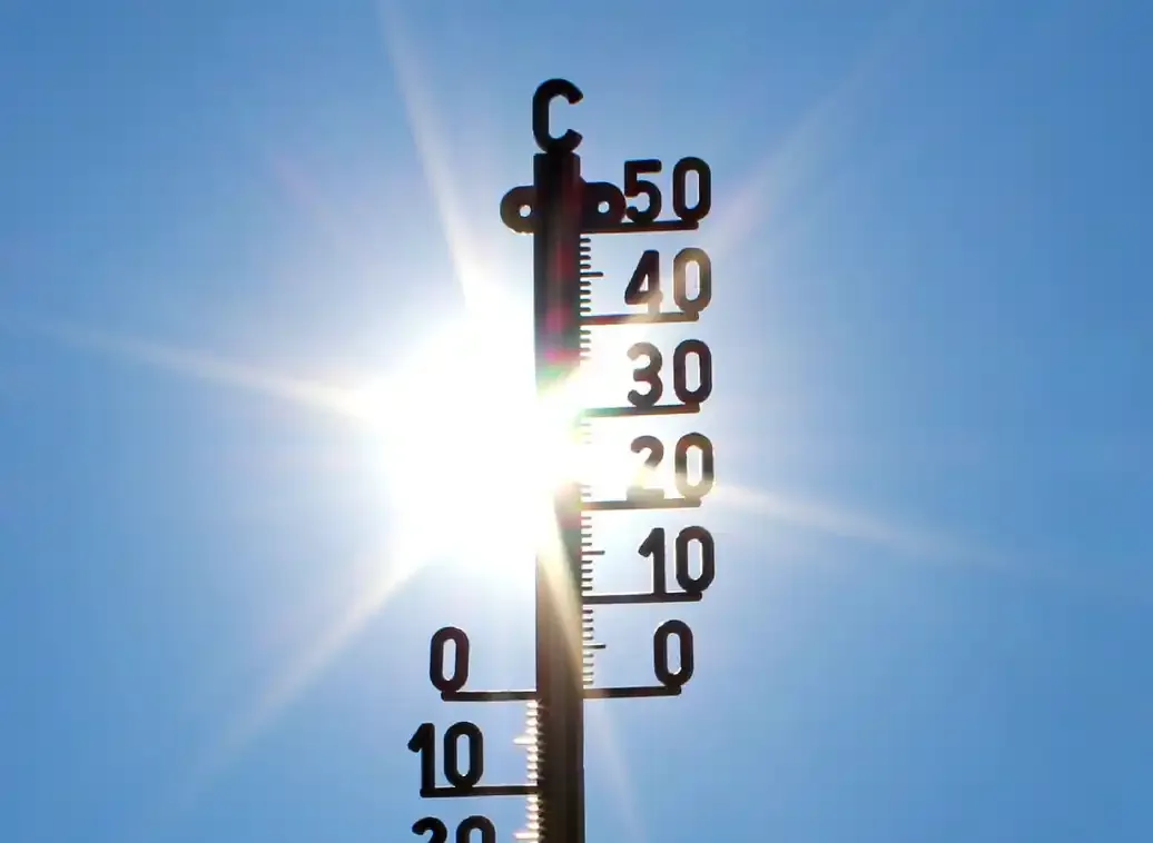Thermometer vor blauem Himmel und Sonnenschein