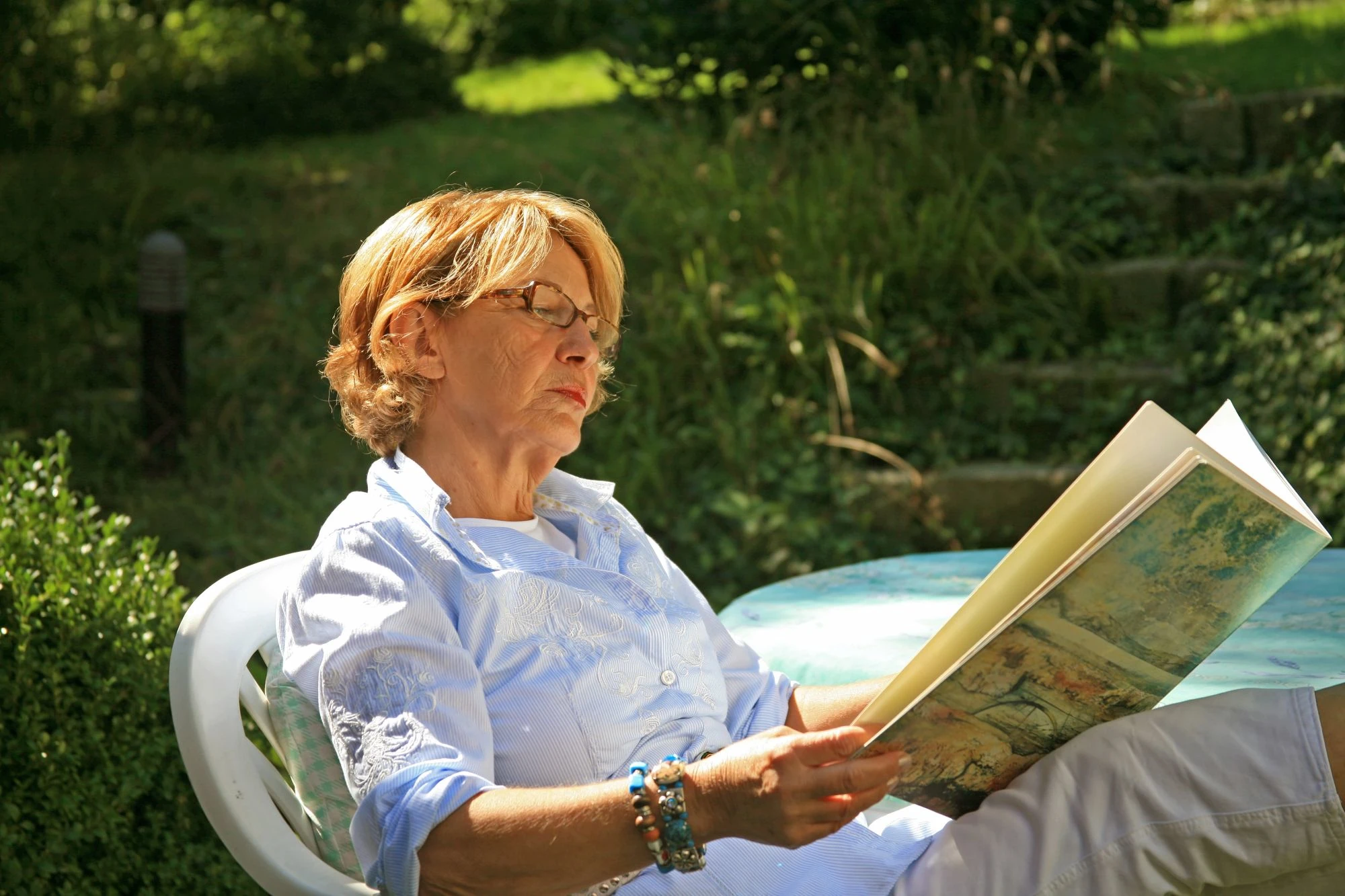 Ältere Frau liest im Garten